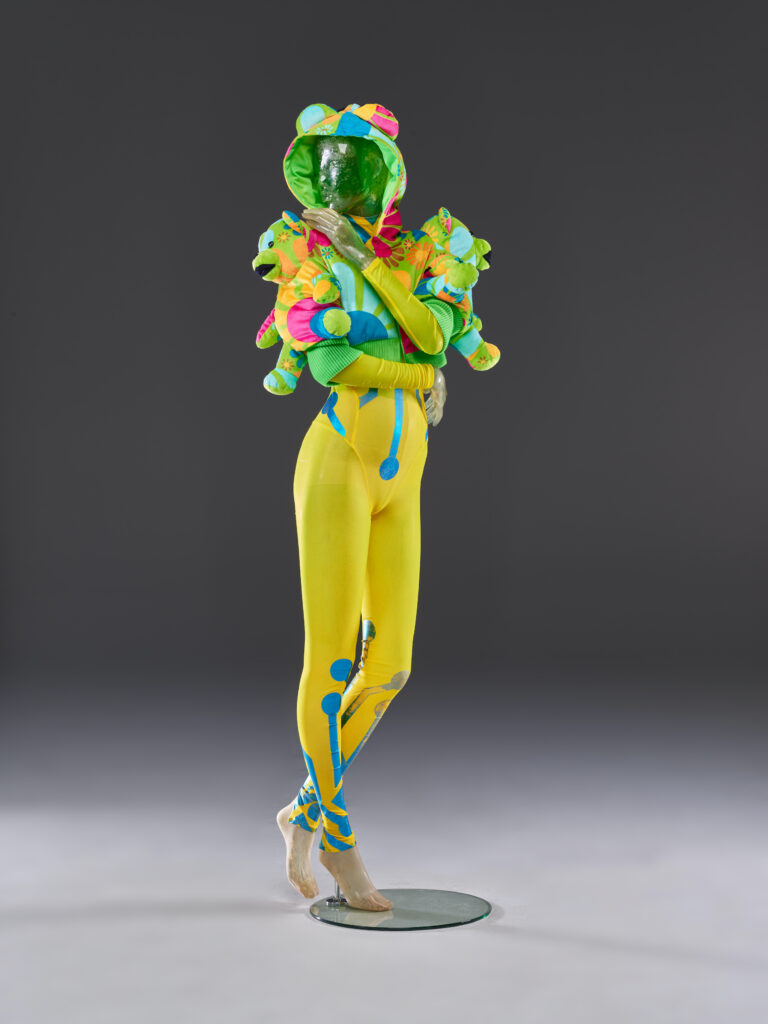 Catsuit und Teddy-Jacke, 1990er Jahre Zu einem hautengen elastischen Catsuit mit grafischen Metallic-Elementen kombiniert Susanne Bartsch eine Plüsch-Jacke mit Teddybären und tritt damit in einem typischen Techno-Look auf. © Susanne Bartsch. Foto: Schweizerisches Nationalmuseum