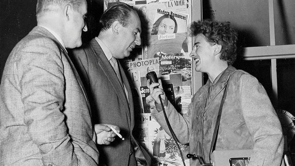 Bild: «Echo der Zeit»-Korrespondentin Annemarie Schwyter während eines Interviews, das Aufnahmegerät unter den Arm geklemmt - Foto: © SRF, 1956