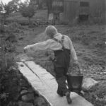 Bis 1981 nehmen Behörden ohne Gerichtsverfahren Hunderttausende Kinder ihren Familien weg. Die Behörden verdingen Kinder auf Bauernhöfe als billige Arbeitskräfte oder platzieren sie in Heimen, geschlossenen Einrichtungen sowie Strafanstalten. Oft müssen sie dort Zwangsarbeit leisten. Viele werden sexuell ausgebeutet. Sie leiden bis heute unter den Folgen der körperlichen und psychischen Gewalt. Wasser holen an der Quelle, 1947, Unteriberg, Foto Theo Frey, Schwyz.