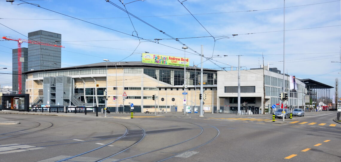 Bild: Hallenstadion Zürich, 2011 - Foto: Roland zh, https://commons.wikimedia.org/wiki/User:Roland_zh -Lizenz: https://creativecommons.org/licenses/by-sa/3.0/deed.en - Datei: https://commons.wikimedia.org/wiki/File:Oerlikon_-_Hallenstadion-Messe_Z%C3%BCrich_2011-03-15_15-20-46.jpg