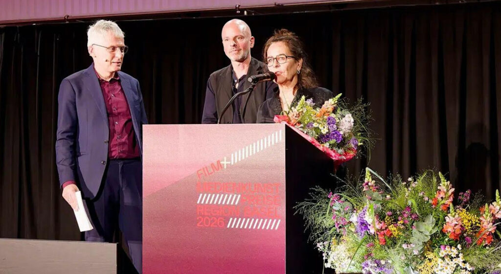 Yves Netzhammer (Mitte) erhält den Basler Filmpreis für «Reise der Schatten», produziert von Stella Händler (rechts). Die Preisverleihung moderierte Tobi Müller (links).