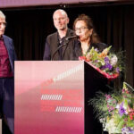 Yves Netzhammer (Mitte) erhält den Basler Filmpreis für «Reise der Schatten», produziert von Stella Händler (rechts). Die Preisverleihung moderierte Tobi Müller (links).