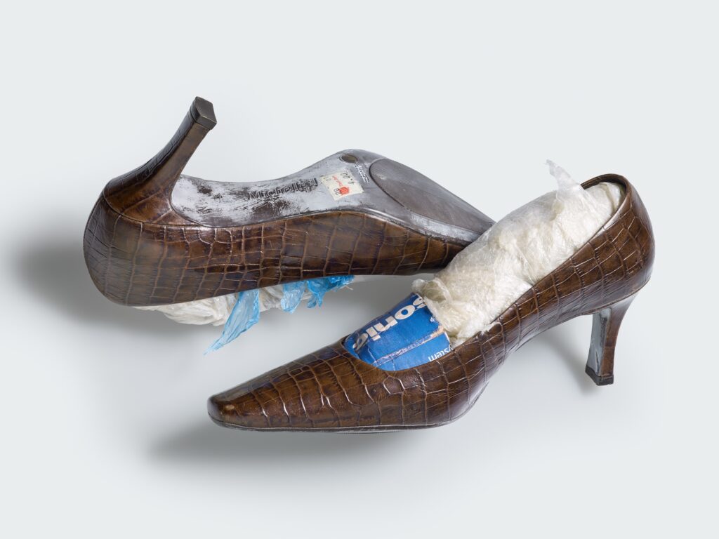 Verschiedene Schuhe aus der Sammlung des Völkerkundemuseums UZH führen als roter Faden durch die Ausstellung. Im Bild: Pumps, Modell «Michelle D», vom Karume-Markt für Secondhand-Kleidung in Daressalam (Tansania). Namen wie «Grossmutterschuh» oder «schicke Schwester» sind Teil der Verkaufsstrategie der Schuhhändler. Inv.-Nr. 33894a/b. Foto: Kathrin Leuenberger, 2026.