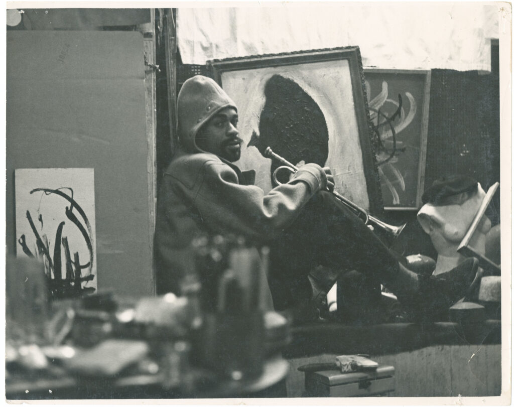 Ted Joans dans son studio d’Astor Place avec en arrière-plan la peinture Bird Lives! et quelques œuvres de la série Jazz Action, vers 1958 Tirage photographique, 20,3 × 25,2 cm Courtesy The Estate of Ted Joans © Droits réservés Photo : Laura Corsiglia
